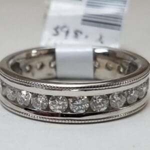 Silver ring with embedded diamonds and tag.