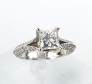 Princess-cut diamond engagement ring on stand.
