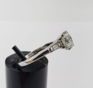 Silver engagement ring with diamond on display.