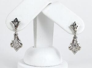 Silver diamond earrings on display stand.
