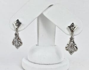 Silver dangle earrings on display stand.