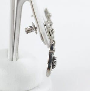 Silver earrings on a display stand.