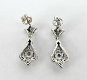 Silver ornate drop earrings on white background.