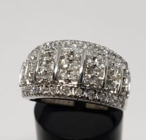 Diamond-encrusted silver ring on black stand.