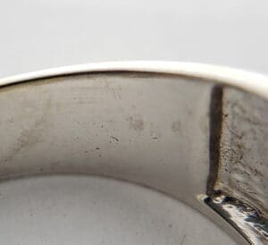 Close-up of a scratched silver ring.