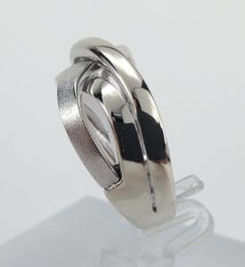 Silver intertwined rings on a clear stand.