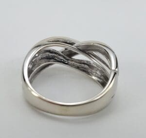 Silver intertwined band ring on white background.