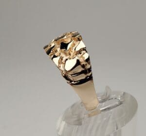 Gold ring with textured design on display.