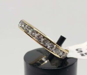 Gold ring with diamonds on display stand.