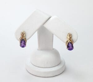 Gold earrings with purple teardrop gemstones.