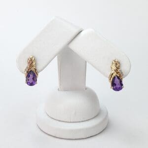 Gold earrings with purple teardrop gemstones.