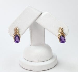 Gold earrings with purple gemstones displayed.
