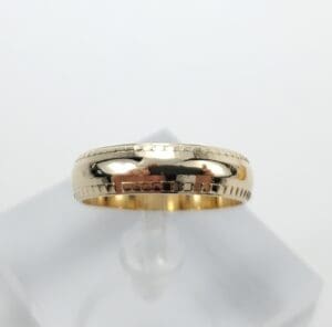 Gold ring with engraved pattern on stand.