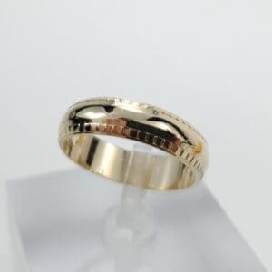 Gold ring with engraved pattern on display.