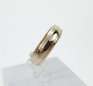 Gold ring with engraved edges on display.