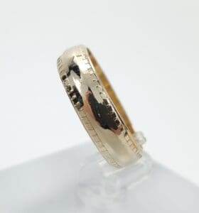 Gold ring with textured edges on display.