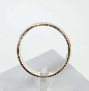 Gold ring displayed on clear stand.