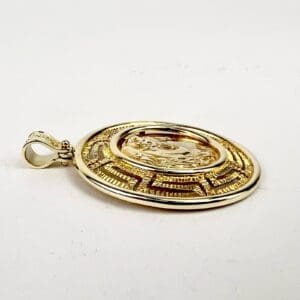 Gold round medallion with intricate design.