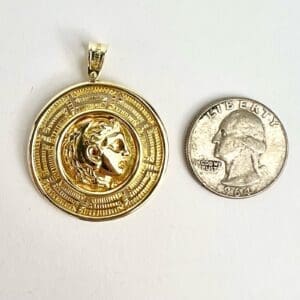 Gold pendant beside a 1964 quarter coin.