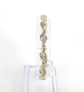 Gold twisted bangle on clear stand.
