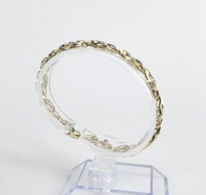 Gold chain bracelet on clear display stand.