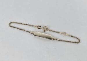 Gold chain bracelet with ID plate.