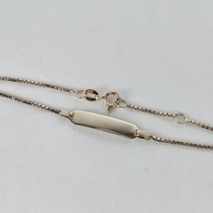 Gold chain bracelet with ID plate.