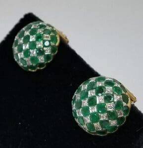 Green gemstone and diamond earrings on display.