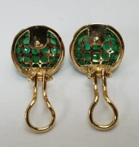 Gold and emerald earrings on white background.
