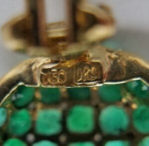 Gold jewelry with green gemstones close-up.