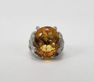 Large yellow gemstone ring with ornate setting.
