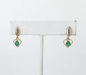 Gold heart earrings with green gemstones.