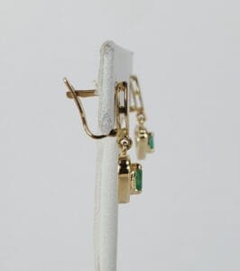 Gold earrings with green gemstone pendants.