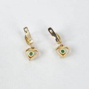 Gold heart earrings with green stones.