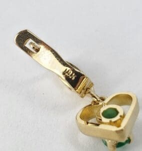Gold jewelry clasp with small green stone.