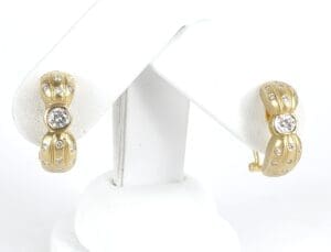 Gold earrings with diamonds on display stand.