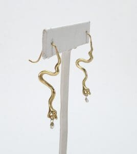 Gold snake earrings with dangling gems.