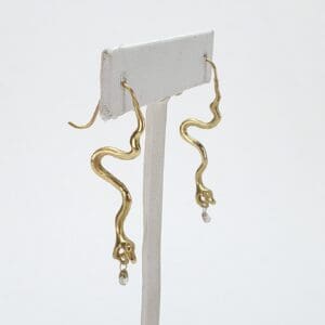 Gold snake earrings with dangling gems.
