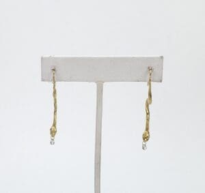 Gold twisted drop earrings on display stand.