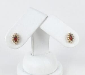 Gold earrings with red gemstones displayed.