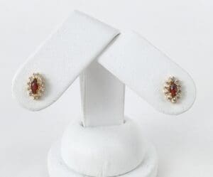 Gold earrings with red gemstones display.