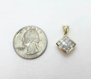Coin next to diamond-patterned gold pendant.