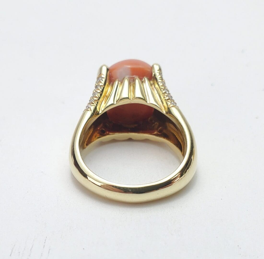Gold ring with orange gemstone setting.