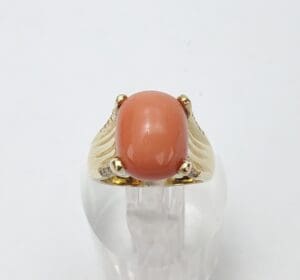 Gold ring with large oval coral gemstone.