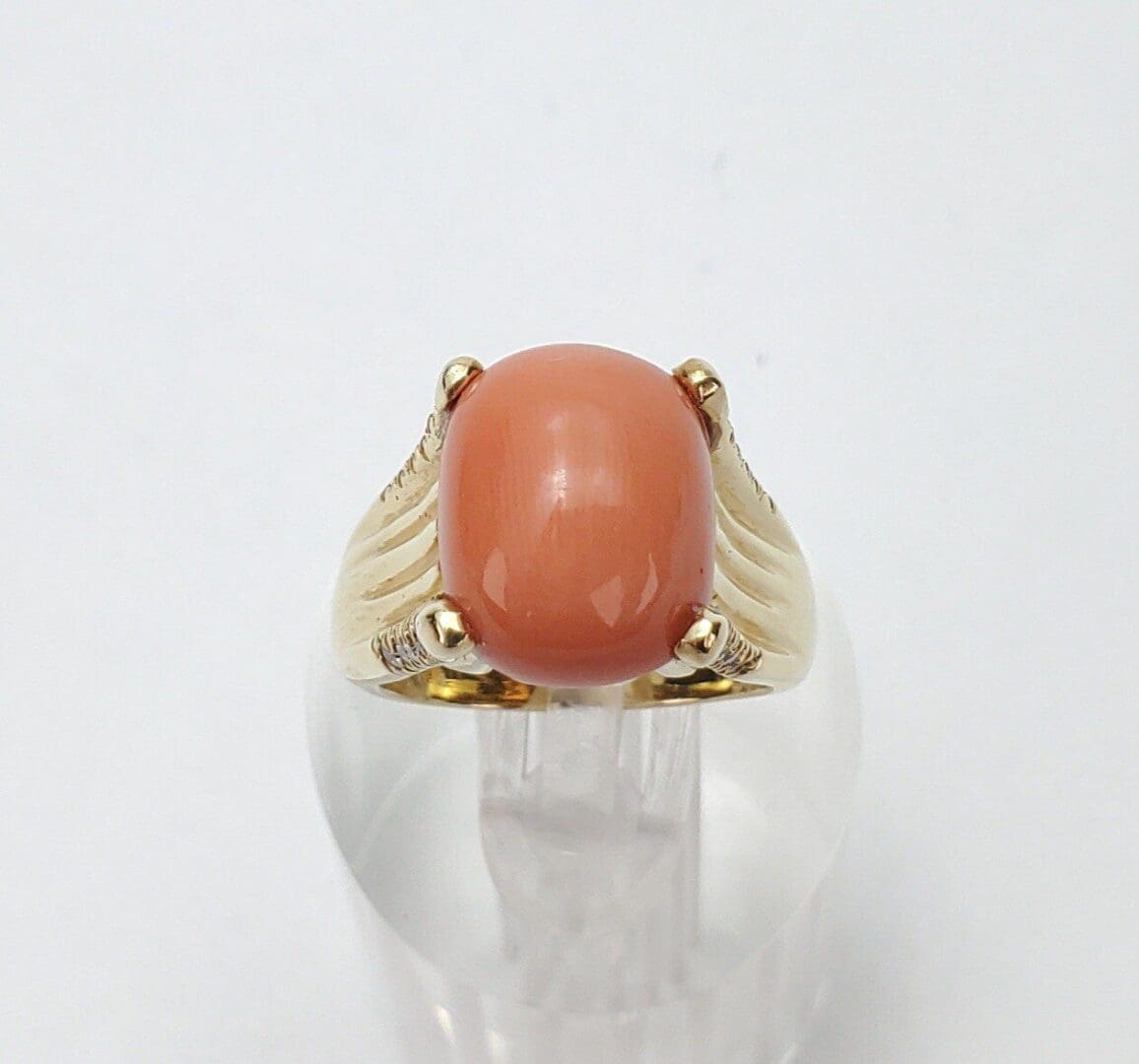 Gold ring with large oval coral gemstone.