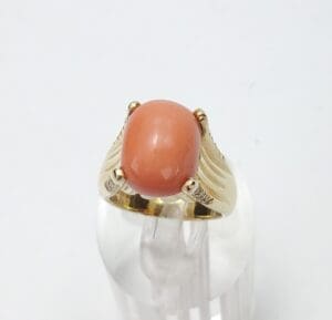 Gold ring with oval coral gemstone.
