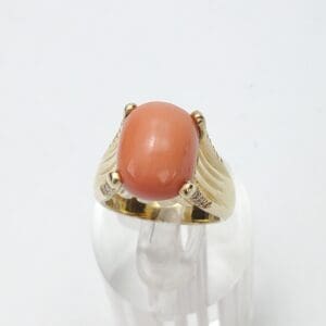 Gold ring with oval coral gemstone.