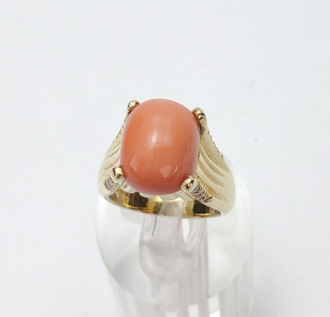 Gold ring with oval coral gemstone.