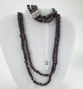 Dark beaded necklace on display stand.
