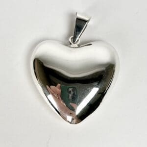 Silver heart-shaped locket with reflection.